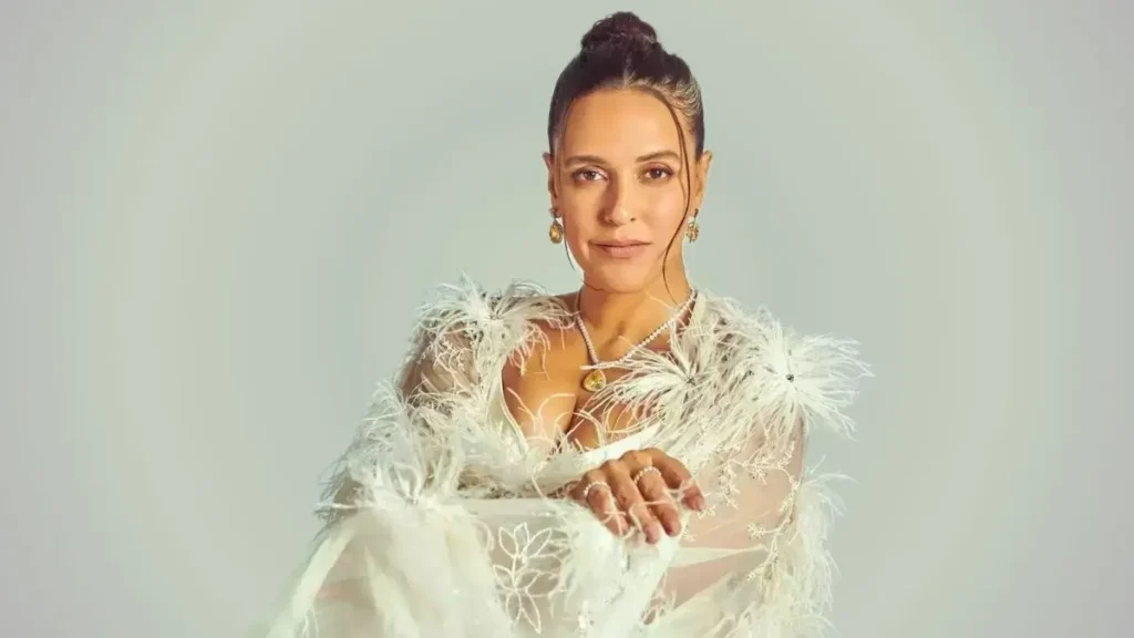 Neha Dhupia in Feathered Outfit Neha Dhupia wearing a white feathered outfit with jewelry, posing against a plain background.