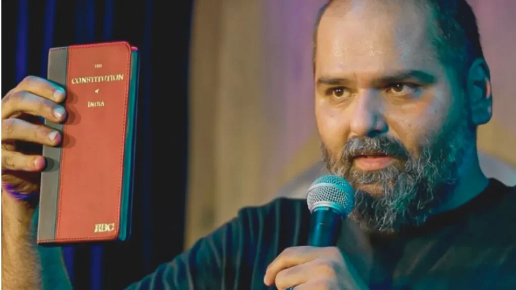 Kunal kamra's bold stance: refusal to apologise for shinde remark Kunal kamra holding the constitution of india, emphasizing his stance on free speech amidst controversy over his remarks on eknath shinde.