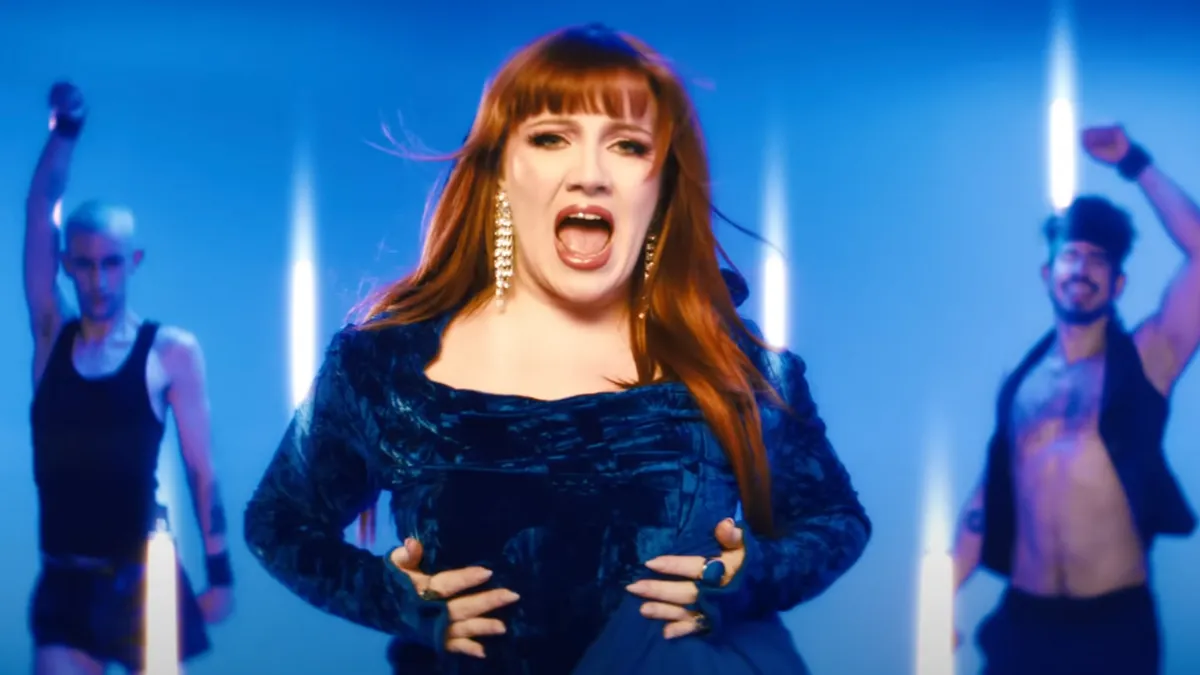 CMAT performing ‘Take A Sexy Picture Of Me’ in a blue velvet outfit with backup dancers and dynamic lighting.