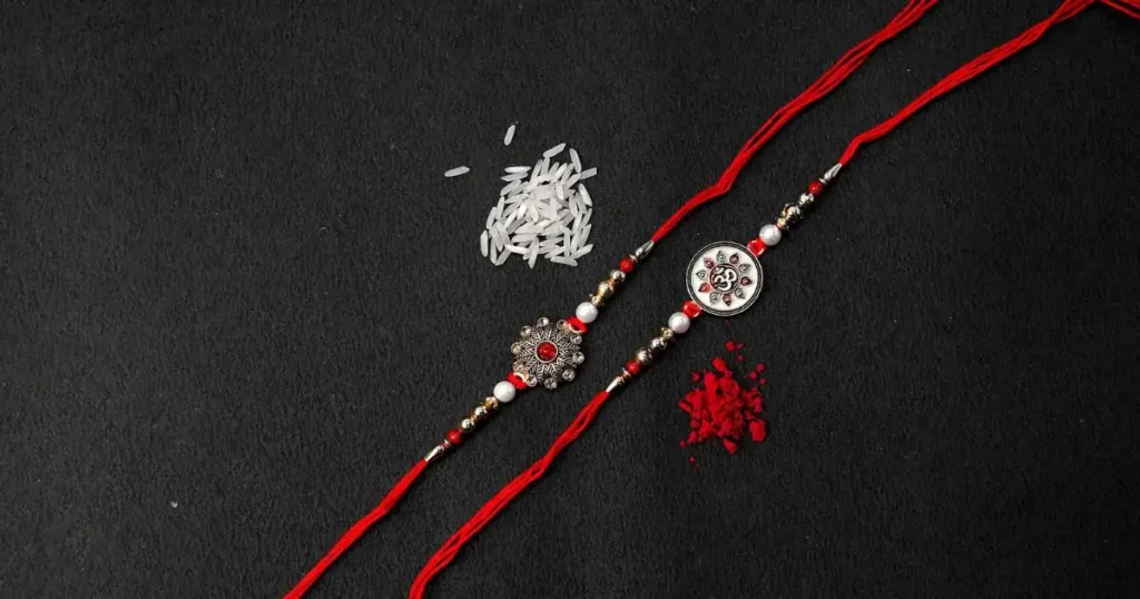 What Is Raksha Bandhan? Meaning, Rituals & How It’s Celebrated in Punjab Photo showing traditional rakhi bracelets, rice, and red roli on black background—symbolizing Raksha Bandhan and its cultural rituals as seen in Punjab.
